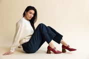 Model wearing an ivory sweater, dark jeans, and red mary jane pumps with a wooden heel.