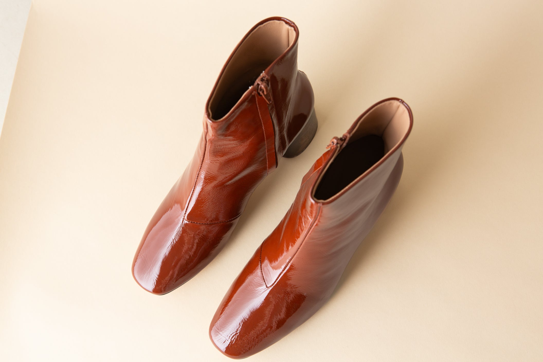 Pair of brown patent leather shoes on a beige background