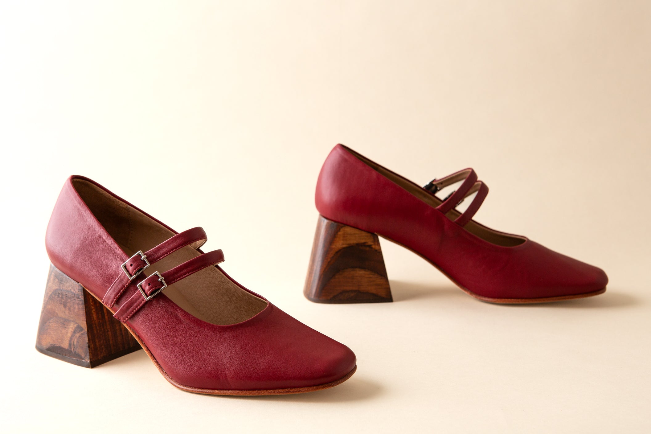 Pair of red shoes with wooden heels on a beige background