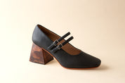 Black shoe with wooden heel on a beige background