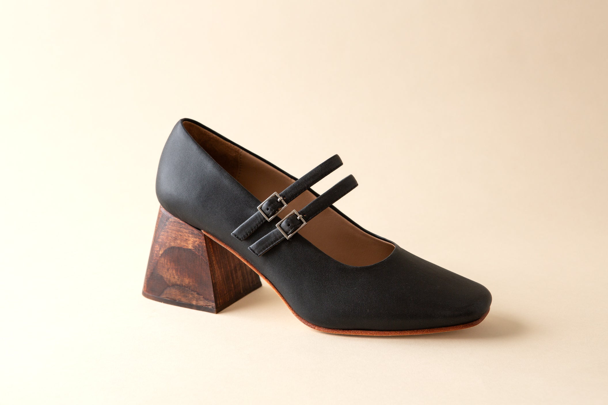 Black shoe with wooden heel on a beige background