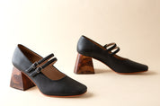 Pair of black shoes with wooden heels on a beige background