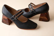 Black high-heeled shoes with wooden heels on a beige background