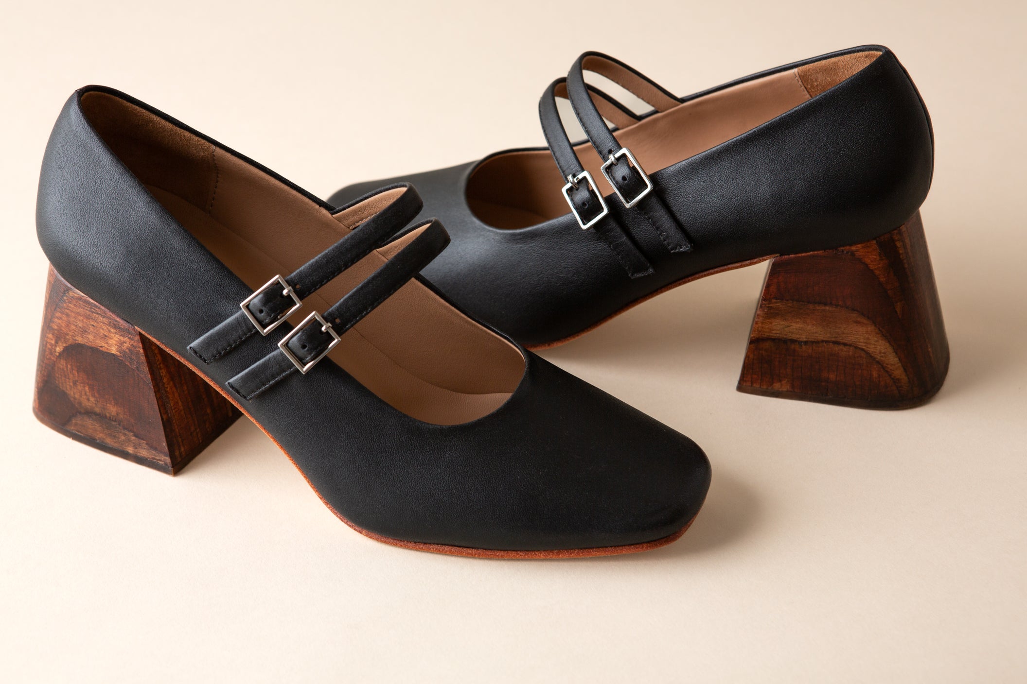 Black high-heeled shoes with wooden heels on a beige background