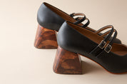 Black high-heeled shoes with wooden heels on a beige background