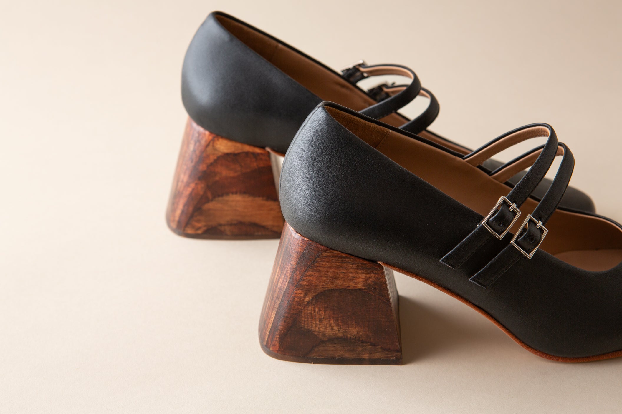 Black high-heeled shoes with wooden heels on a beige background
