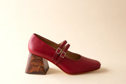 Red shoe with wooden block heel on a beige background