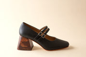 Black shoe with wooden heel on a beige background