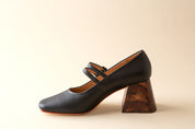 Black shoe with wooden heel on a beige background