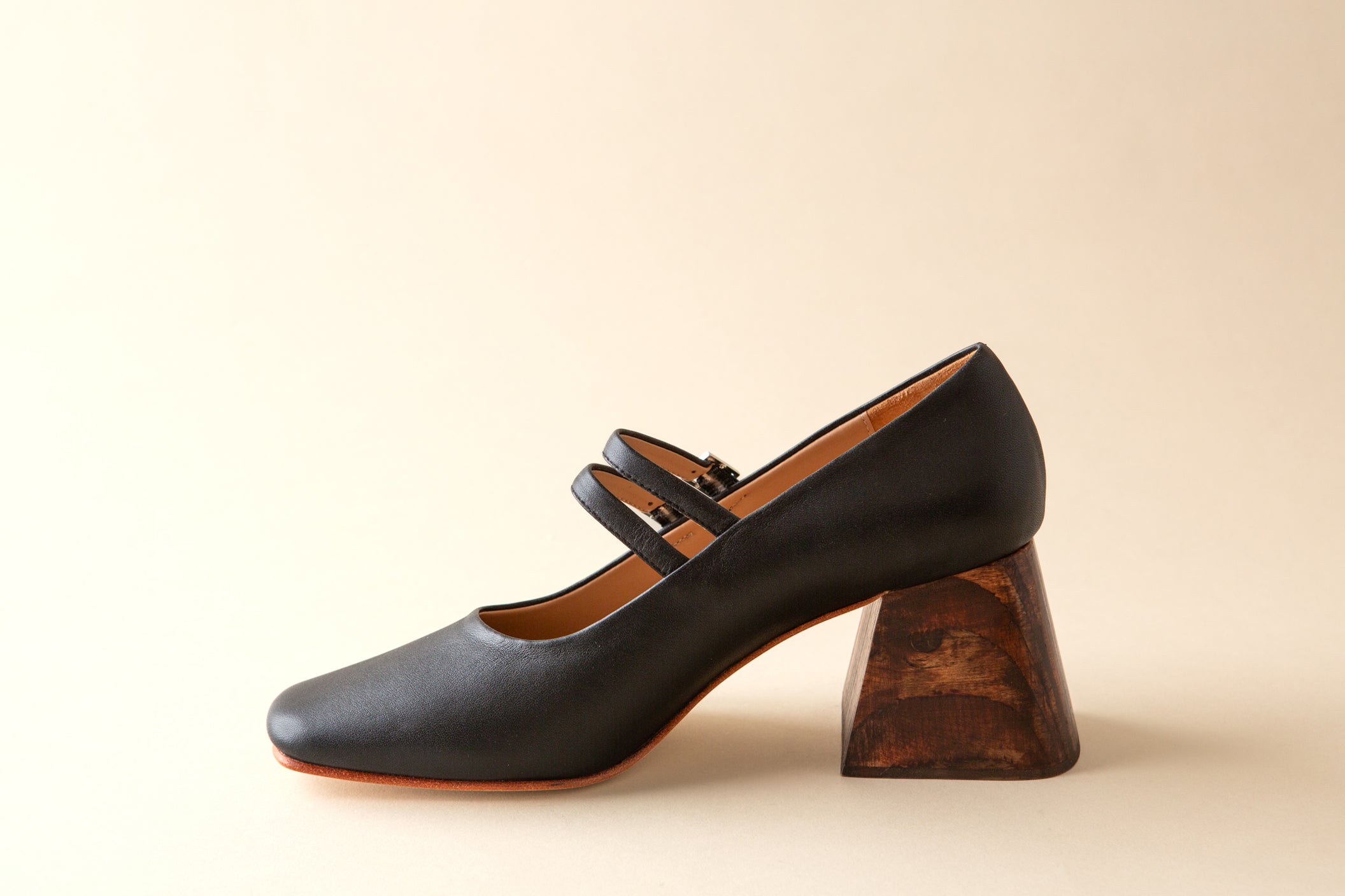 Black shoe with wooden heel on a beige background