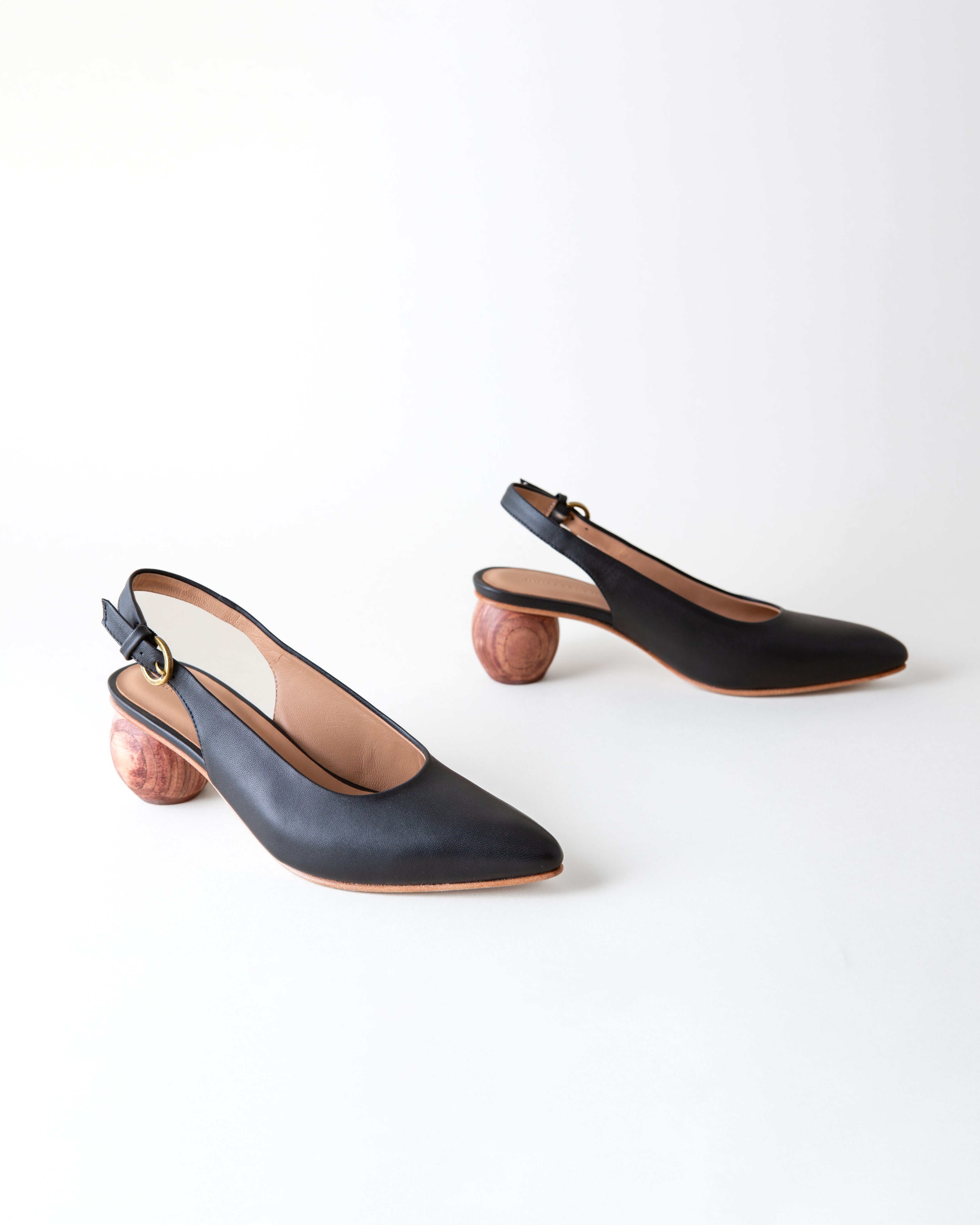 Black high-heeled shoes with slingback design on a white background