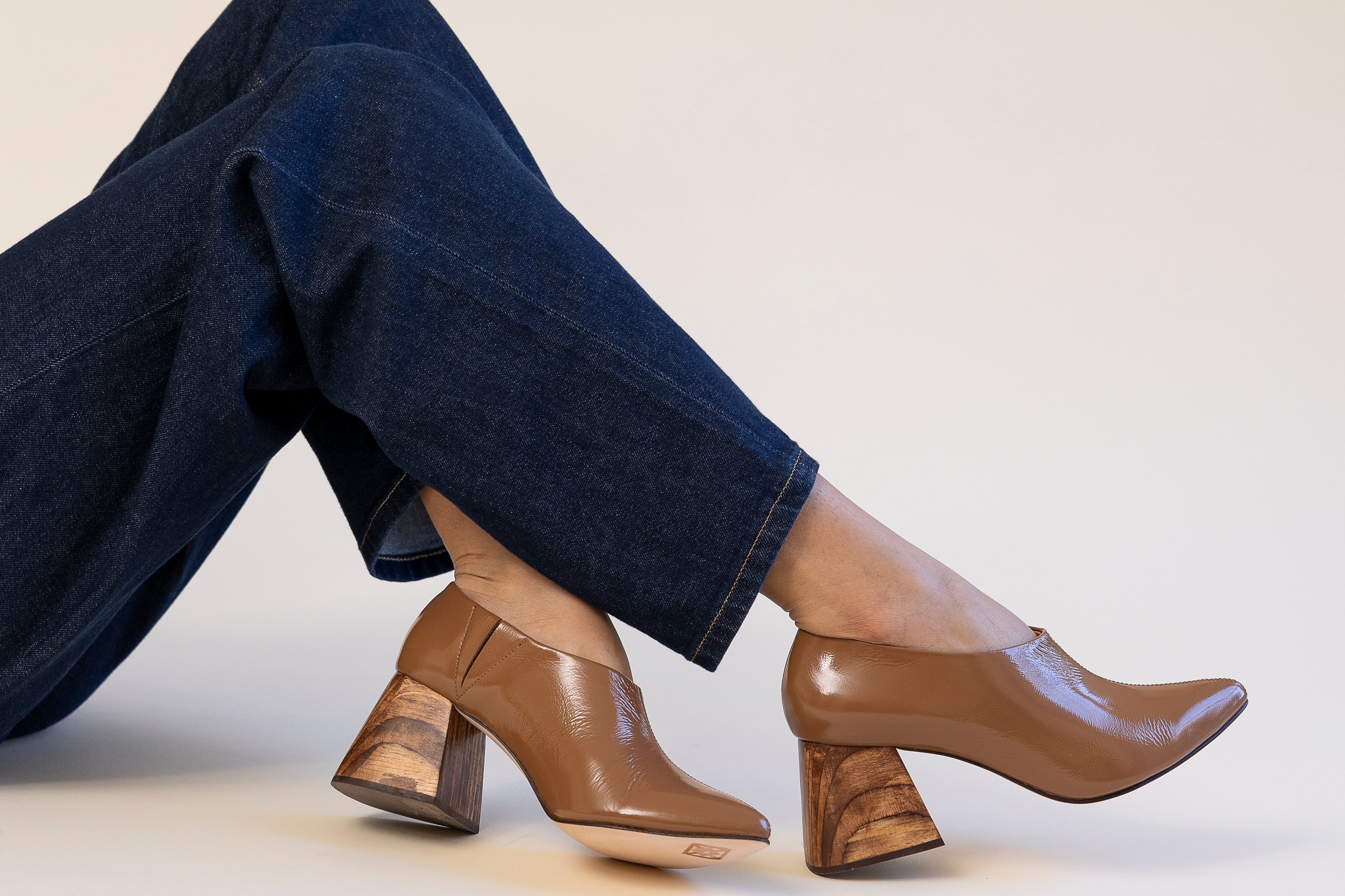 Brown leather shoes worn with dark jeans on a light background