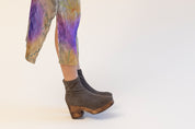 Model wearing grey clog boots with colorful dress on a white background