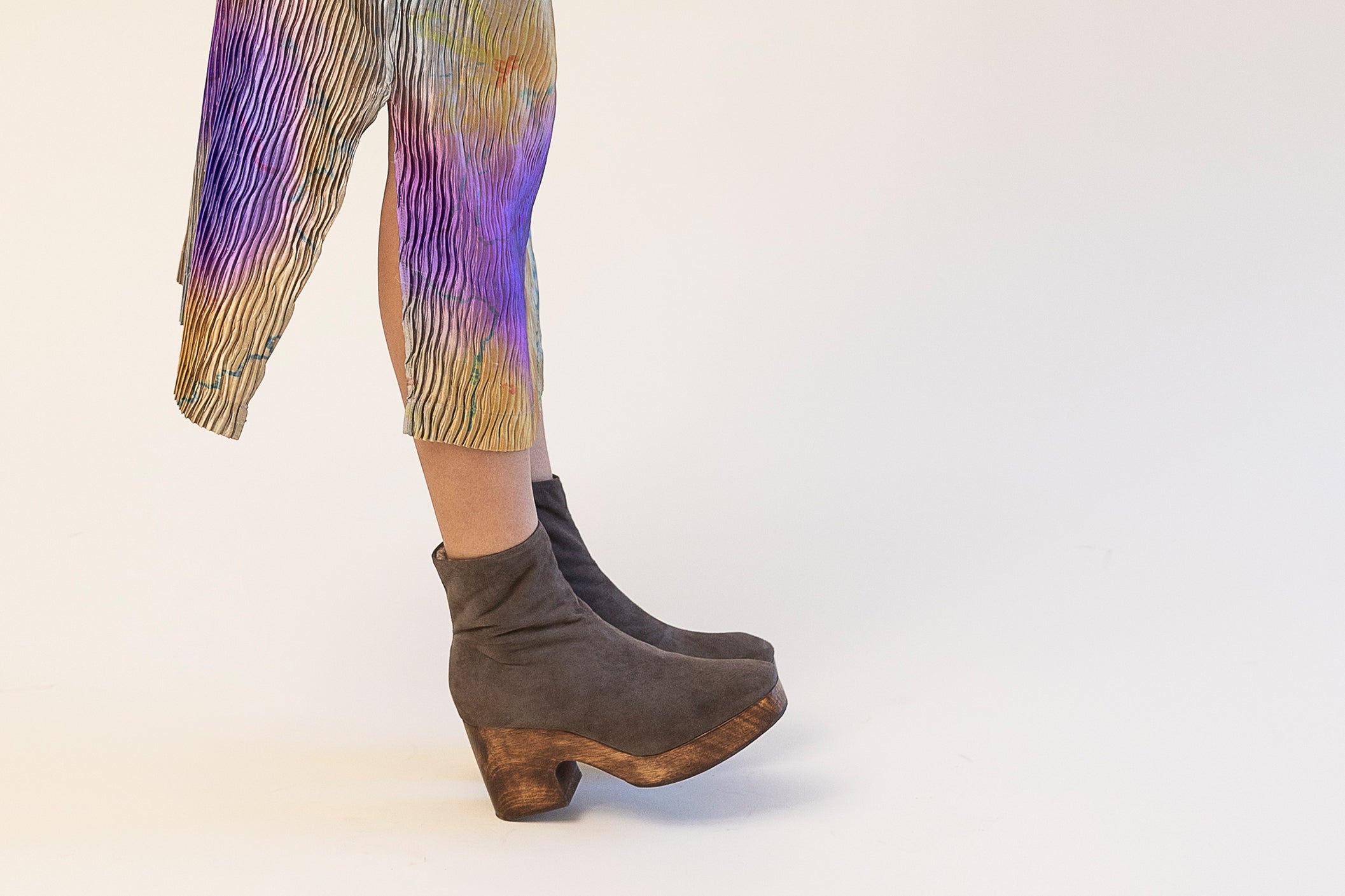 Model wearing grey clog boots with colorful dress on a white background