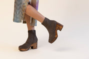 Grey suede clog boots with a wood platform worn with a striped dress on a white background