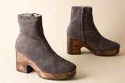 Pair of gray suede ankle boots with wooden soles on a beige background