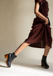 Black leather platform clog boot on woman in dress