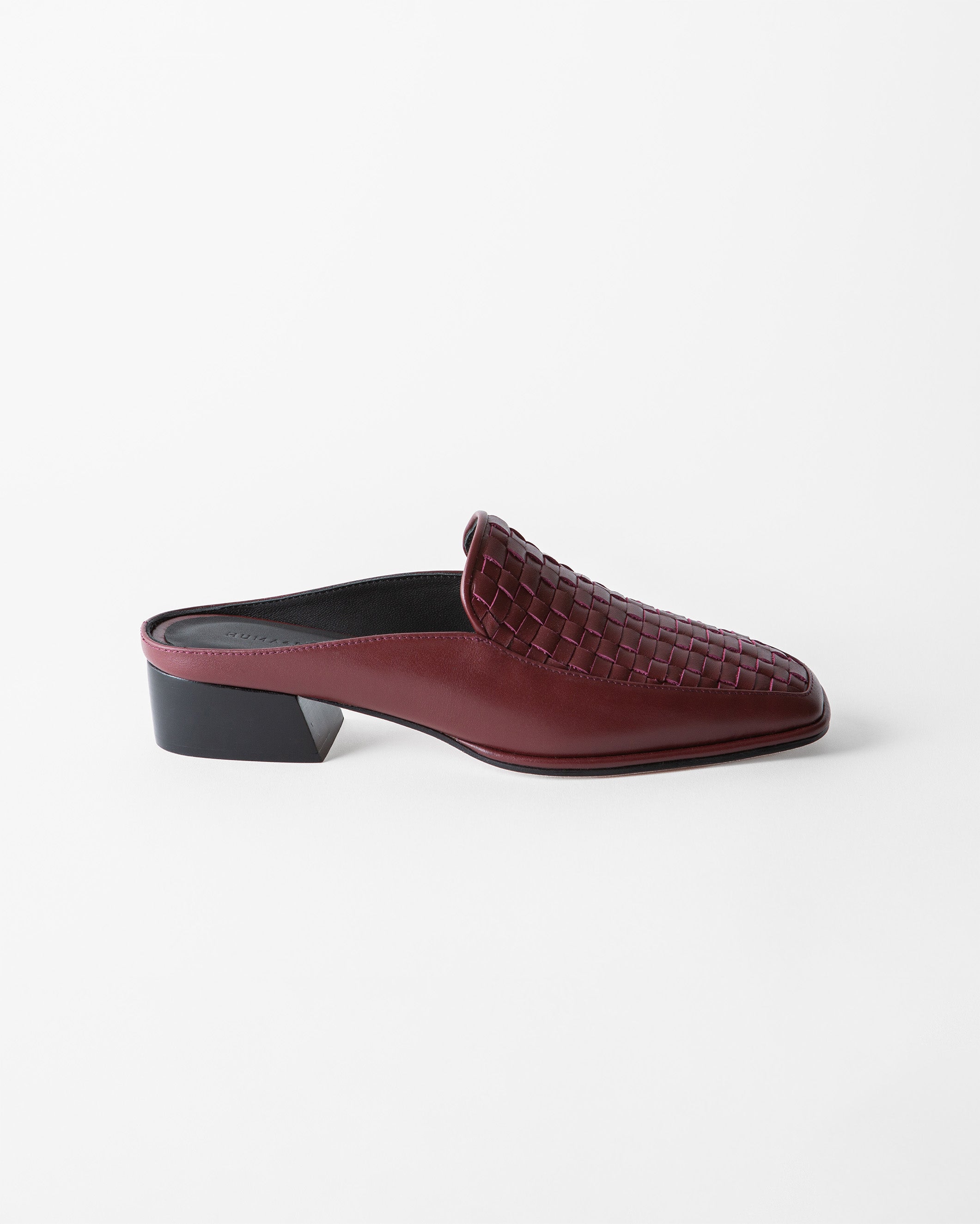 A single burgundy woven leather mule loafer with a low black block heel, shown from a side profile on a clean white background.