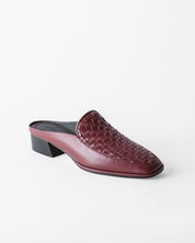 A single women's mule shoe in burgundy leather with a woven pattern on the upper and a low block heel, photographed on a clean white background.