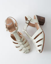Pair of white sandals with brown soles on a light gray background