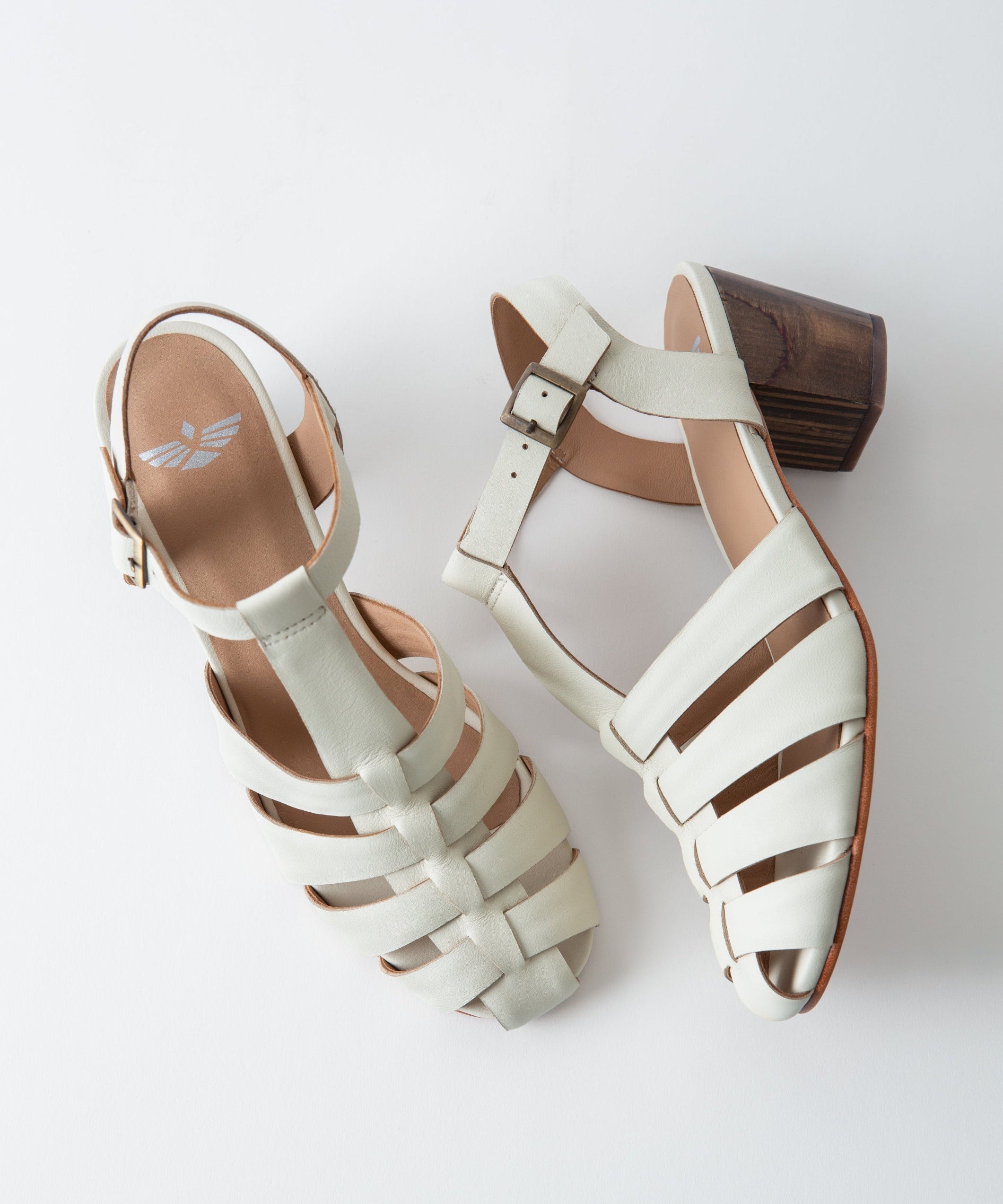 Pair of white sandals with brown soles on a light gray background