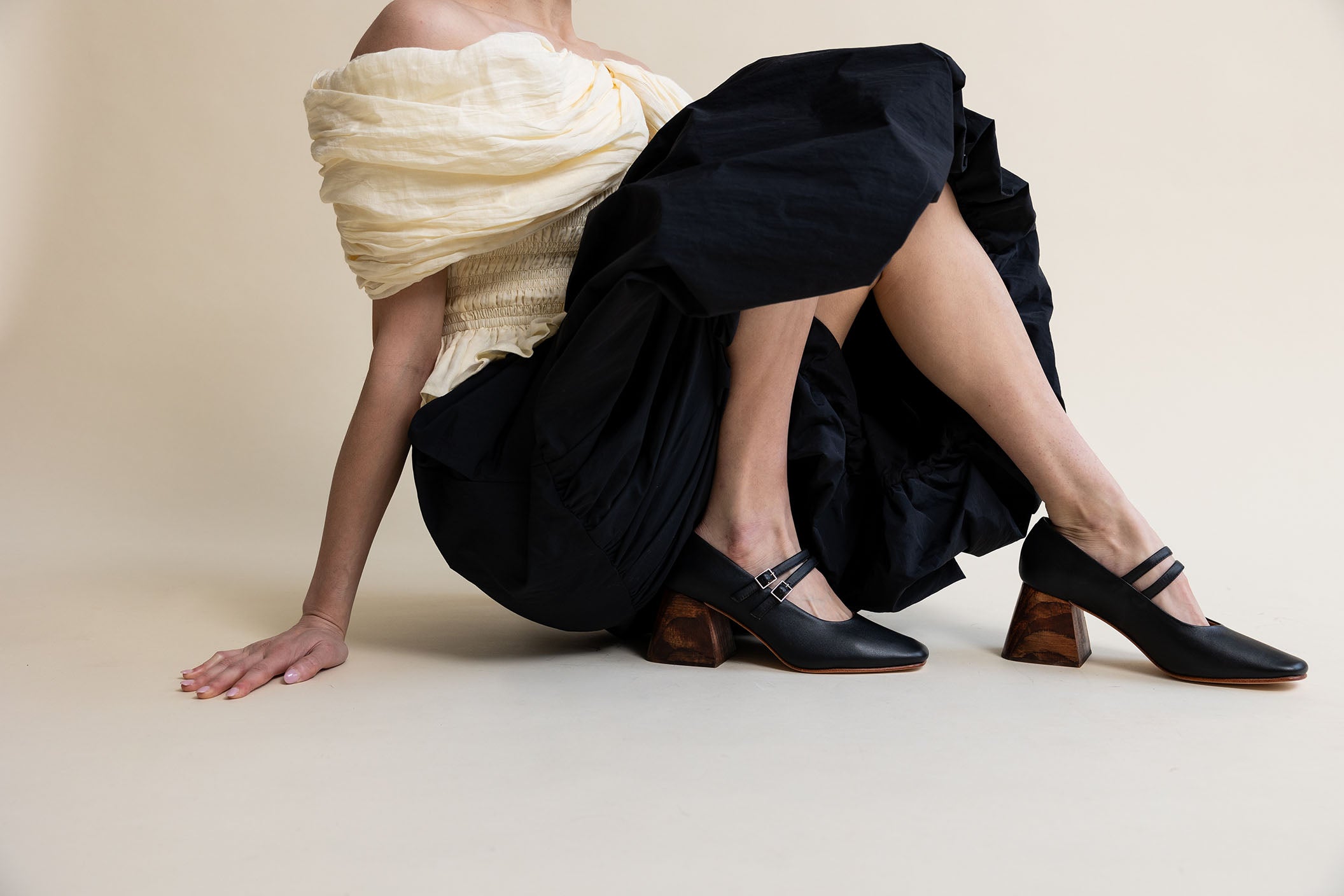 Model wearing an ivory blouse and black skirt with black mary jane pumps with a wooden heel.