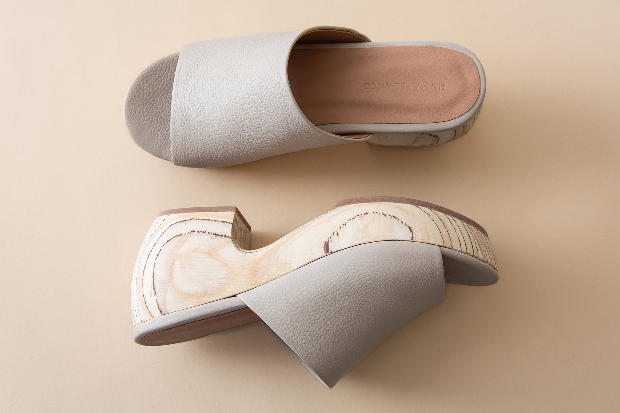 Pair of off-white clog sandals on a beige background