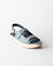 Blue sandal with metallic accents on a light gray background