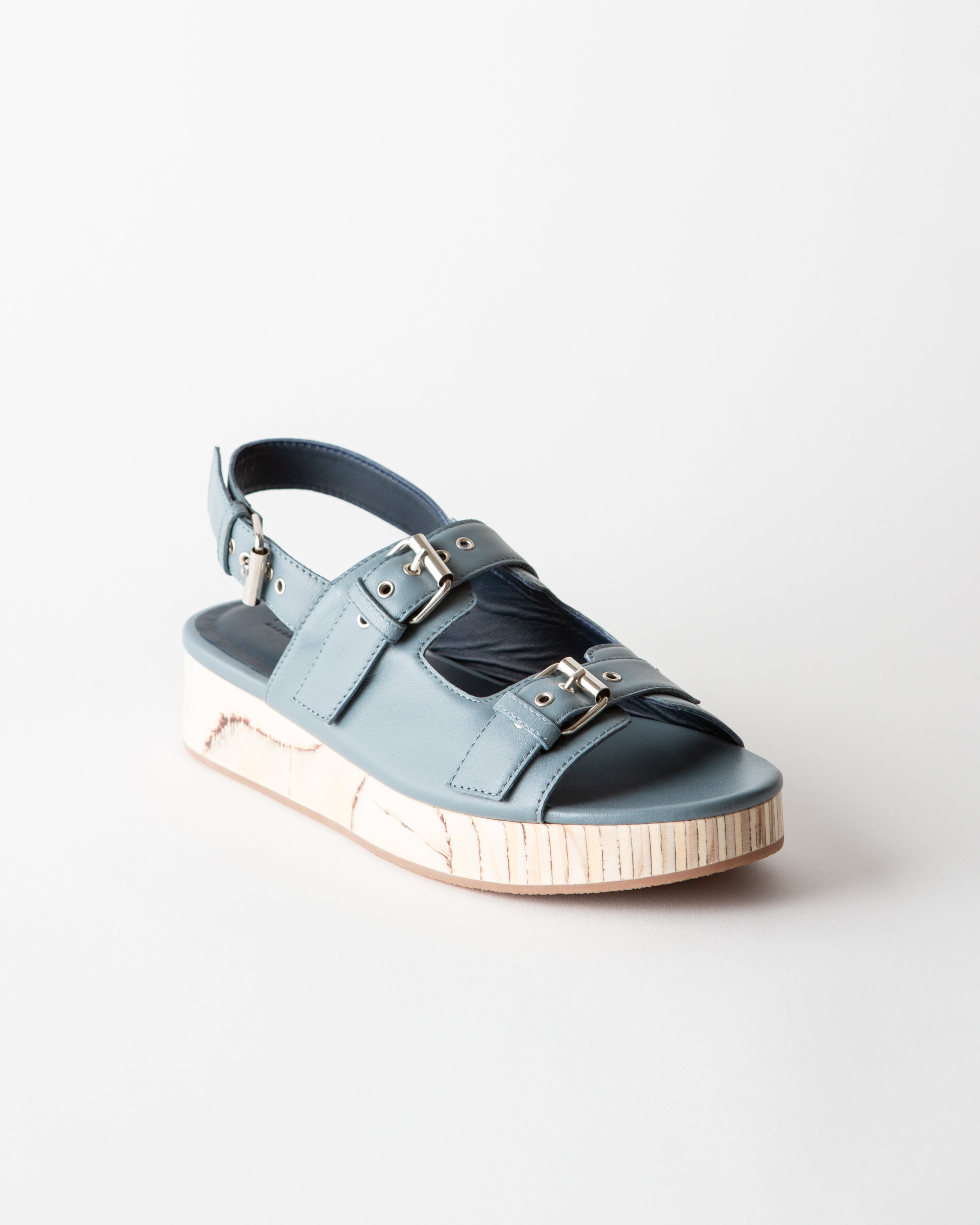 Blue sandal with metallic accents on a light gray background