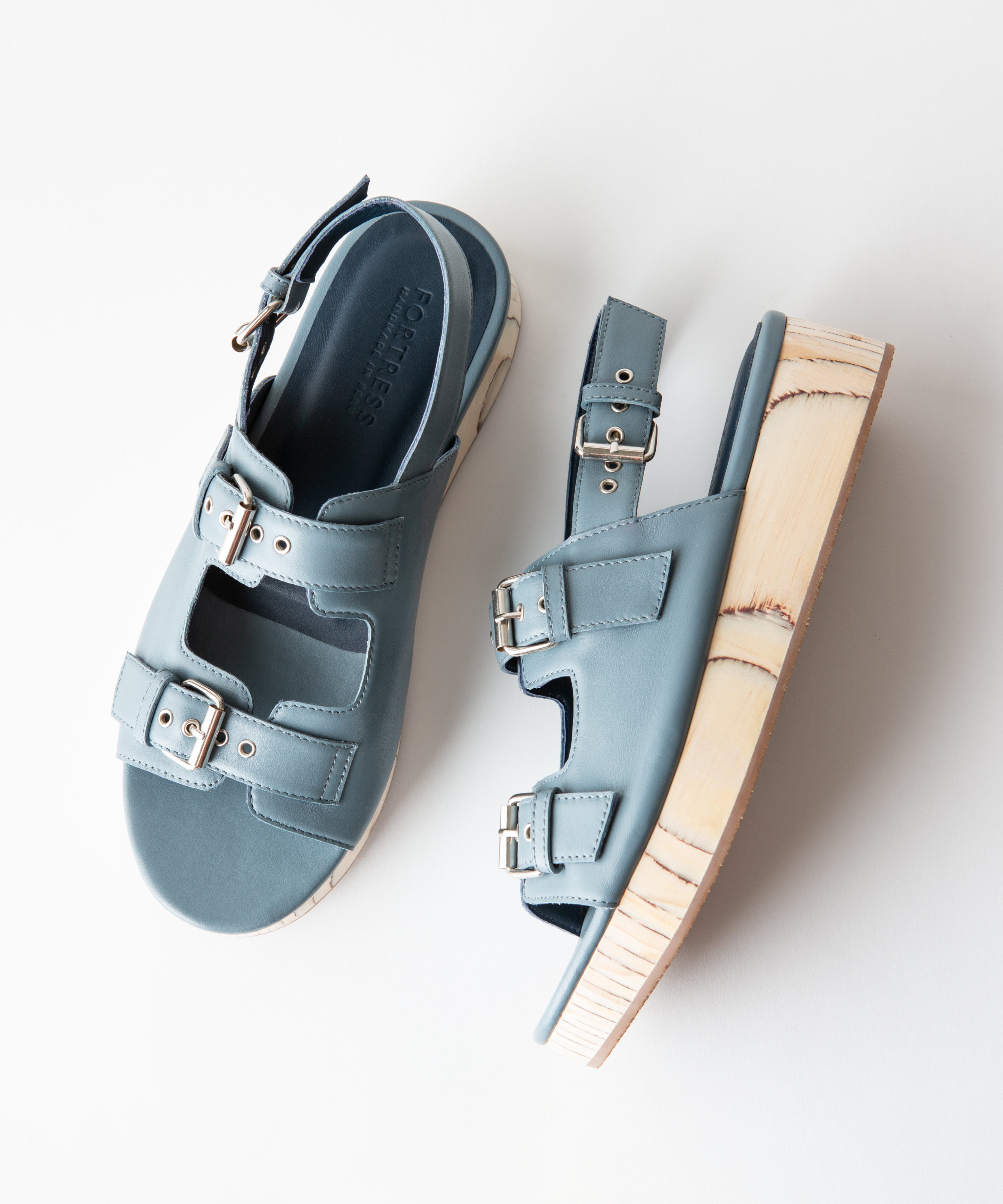Pair of light blue sandals with wooden soles on a white background