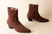 Pair of brown suede ankle boots on a beige background