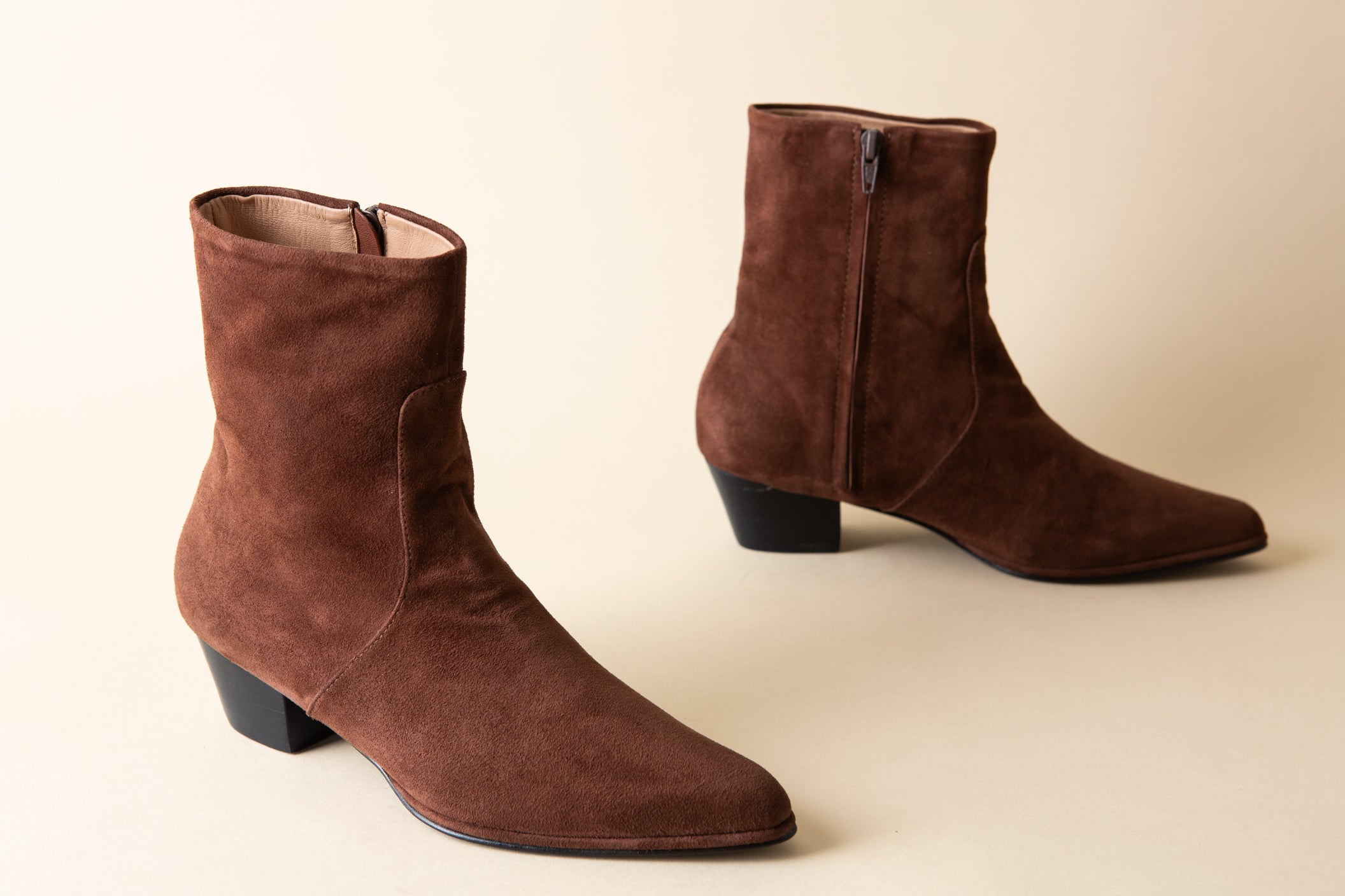 Pair of brown suede ankle boots on a beige background