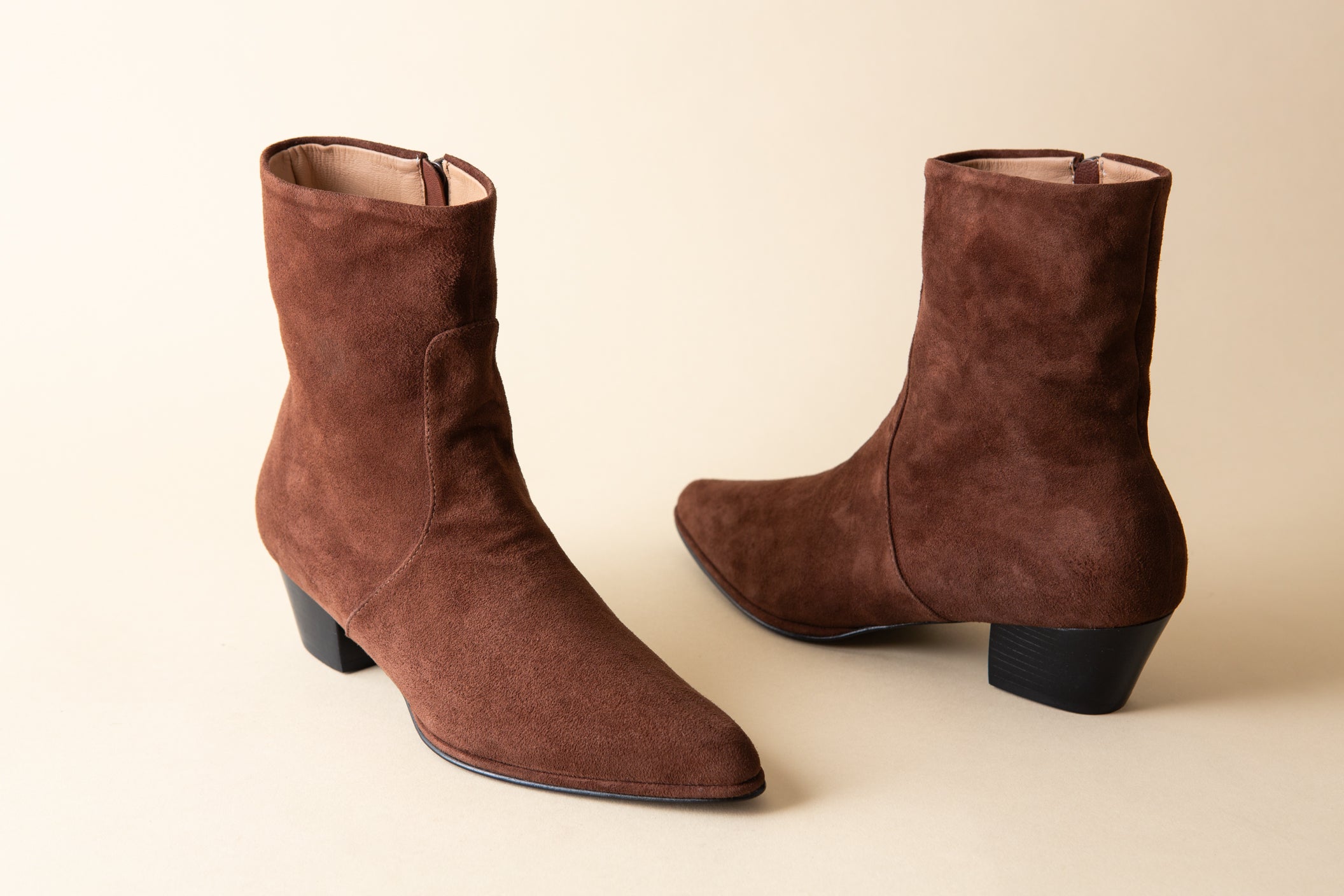 Pair of brown suede boots on a beige background