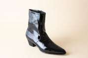 Black patent leather ankle boot on a beige background