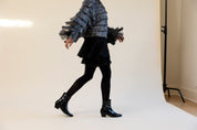 Person wearing a textured sweater and black skirt with black shoes on a white background