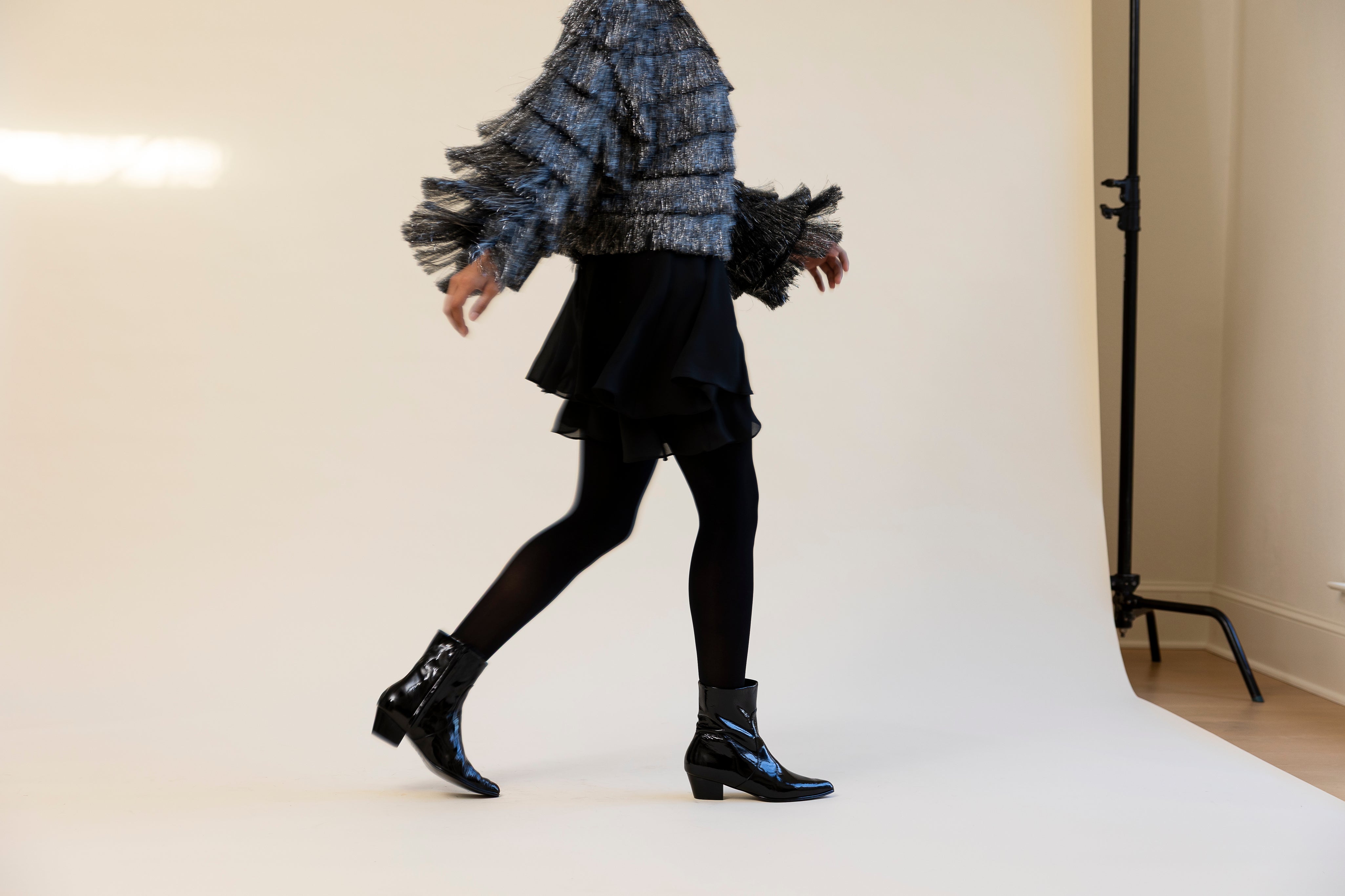 Person wearing a textured sweater and black skirt with black shoes on a white background