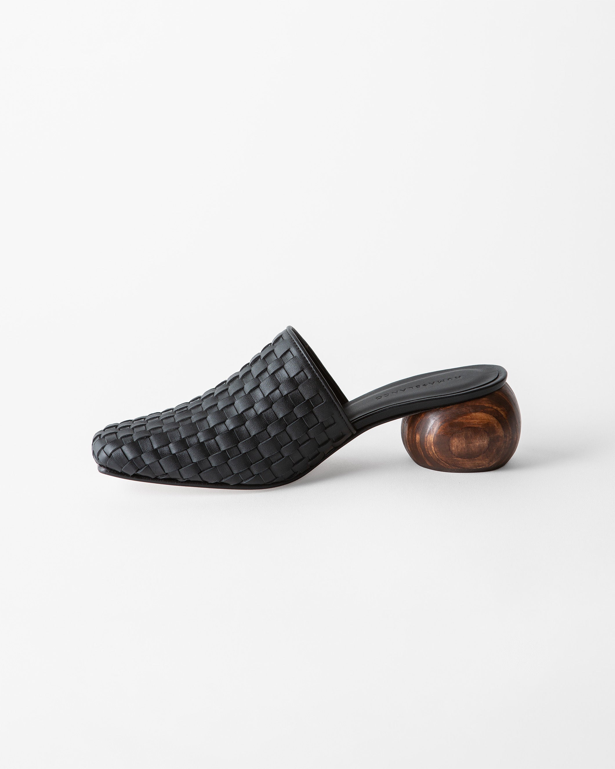 A black woven leather mule slipper with a chunky, spherical wooden block heel, shown from a side profile on a clean white background.