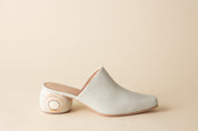 White mule shoe on a beige background