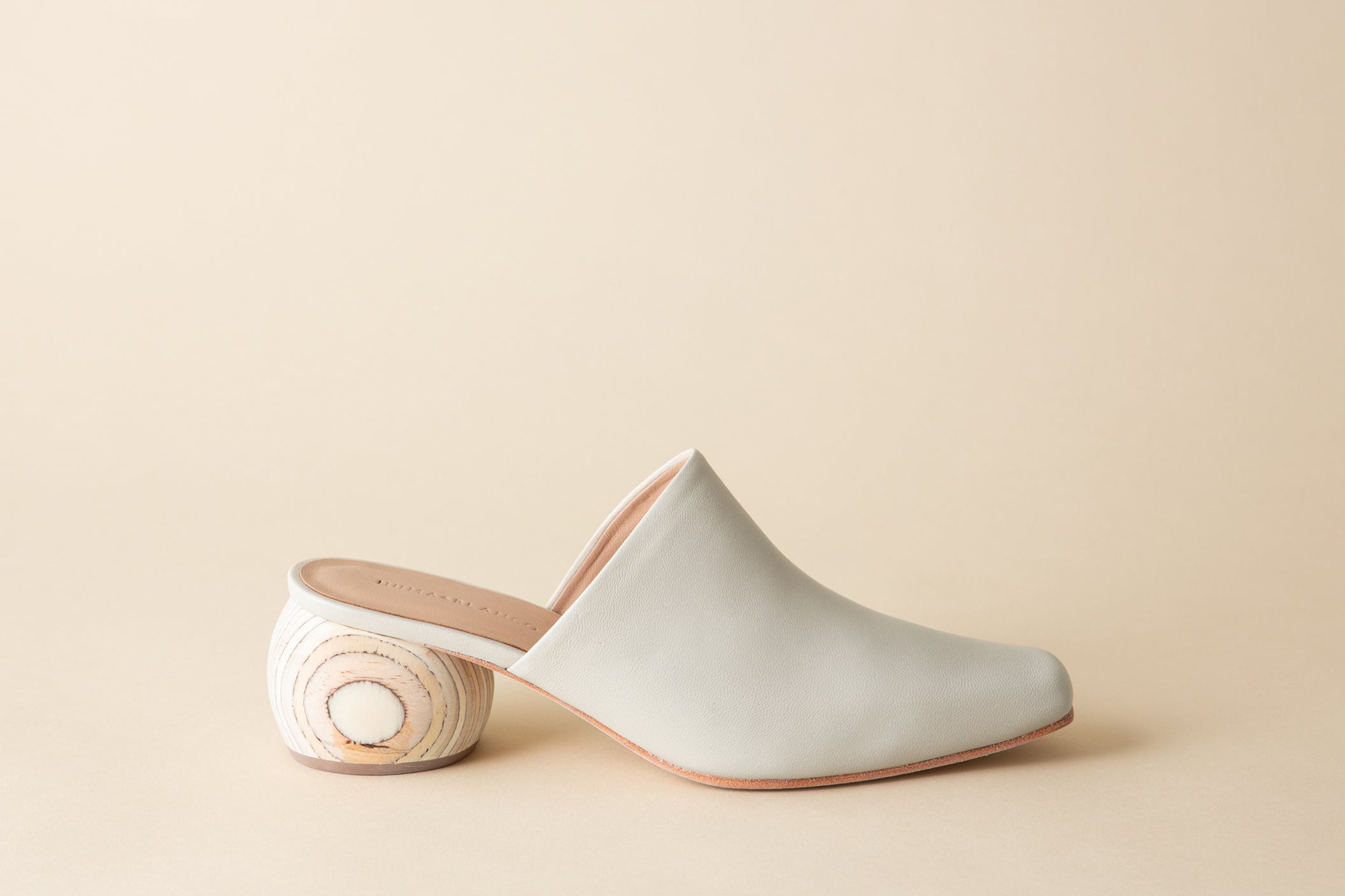White mule shoe on a beige background