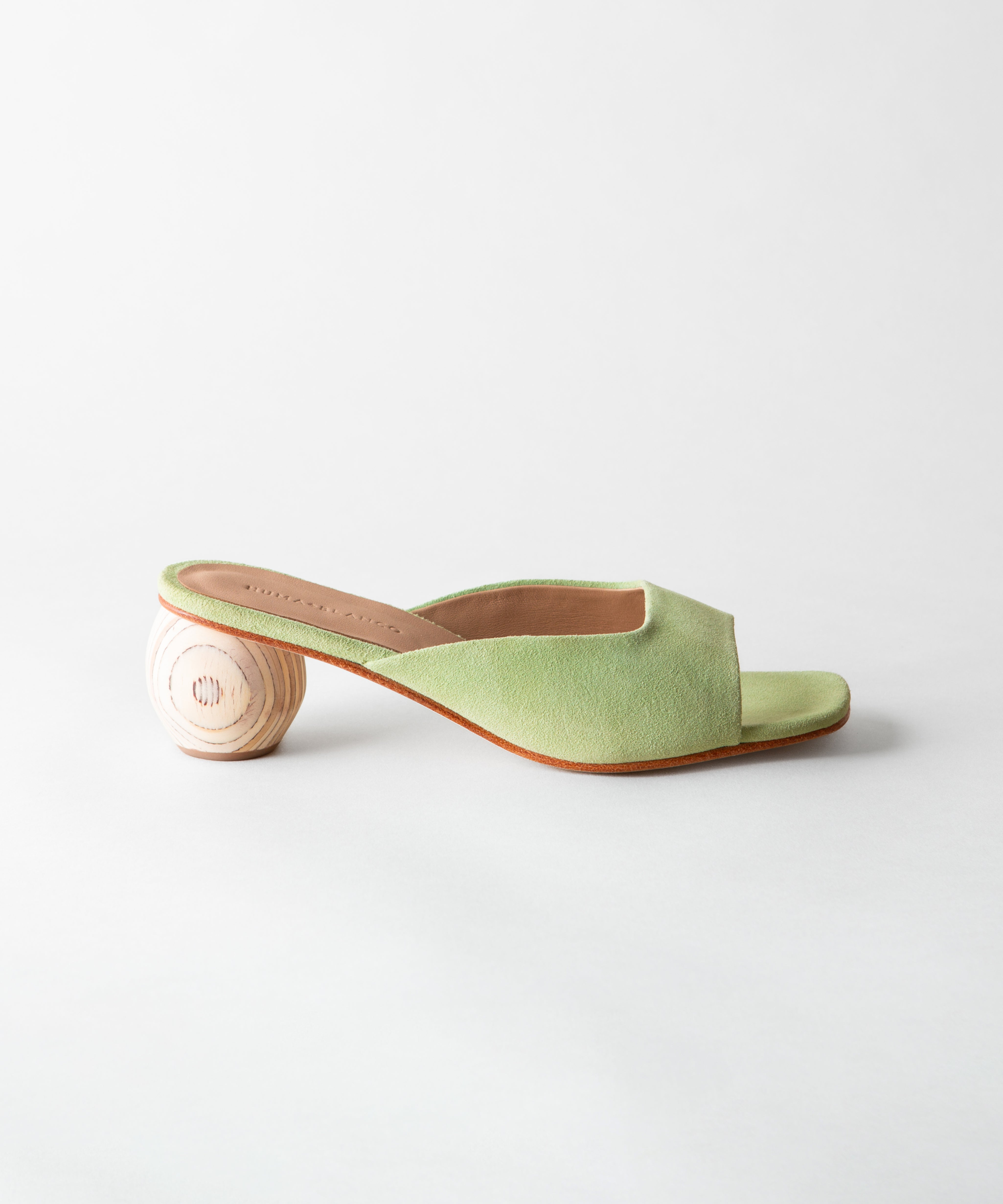 Green sandal with a wooden heel on a light gray background