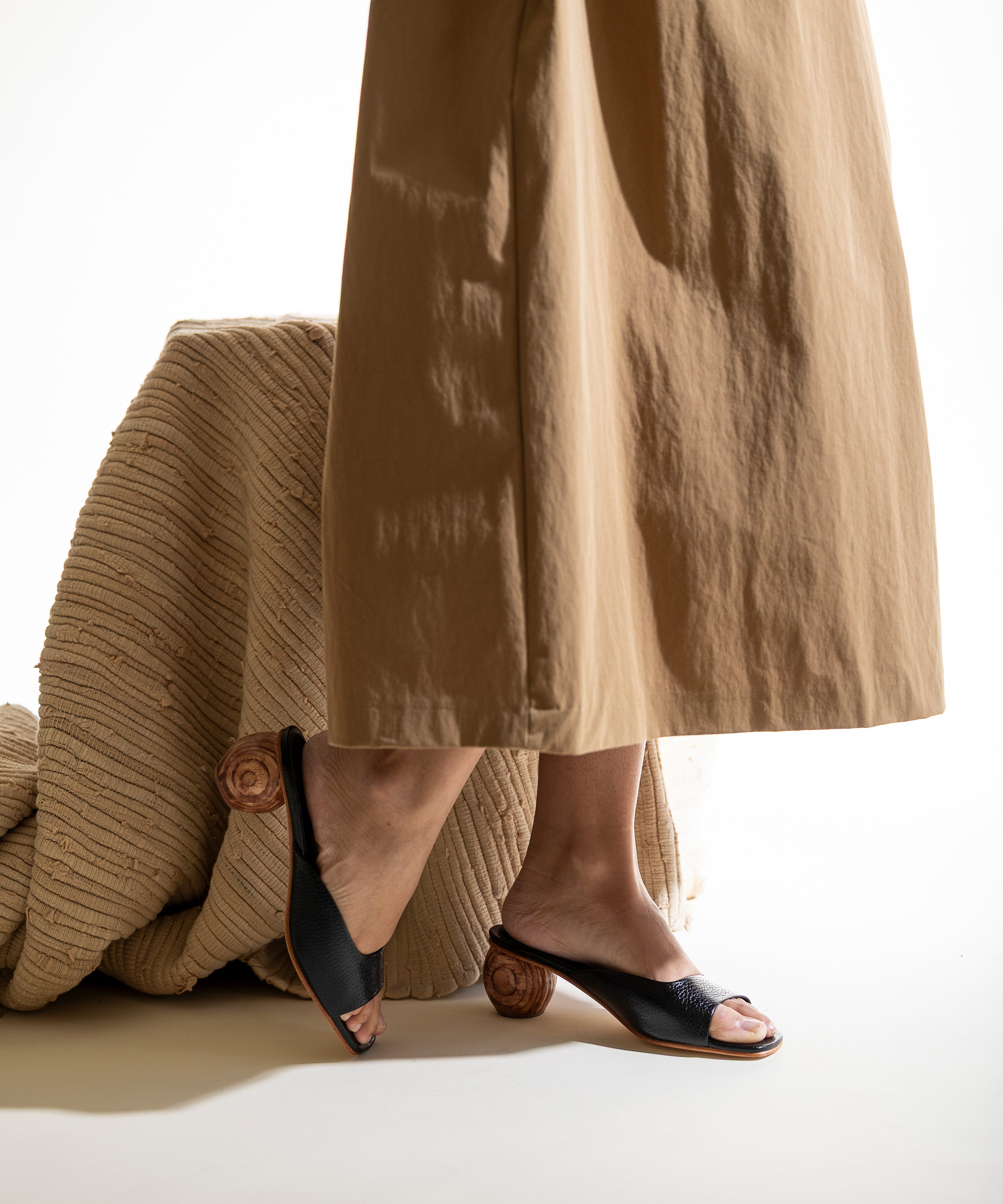 Person wearing a tan skirt and black open-toe sandals with a wood heel