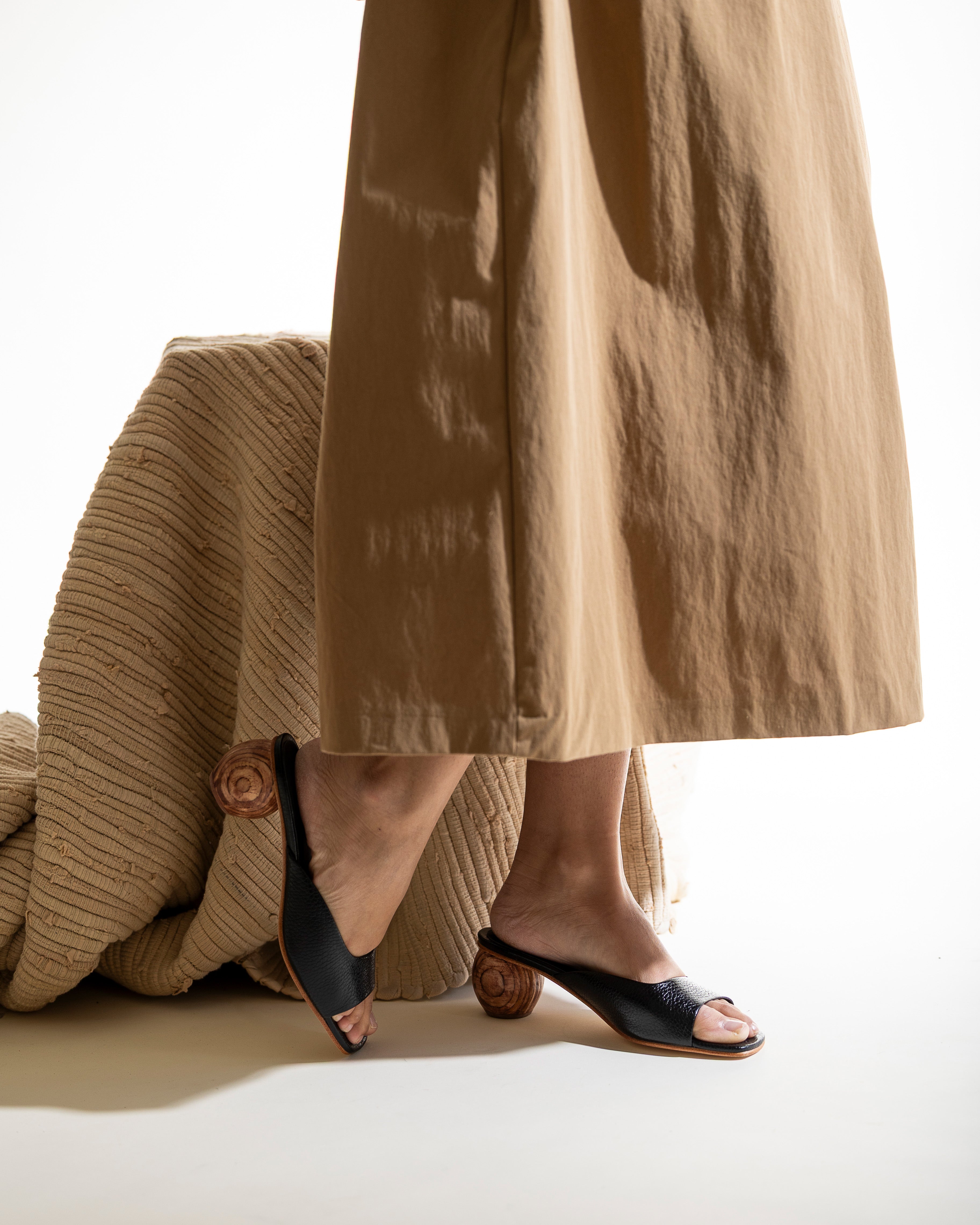 Person wearing a tan skirt and black open-toe sandals with a wood heel