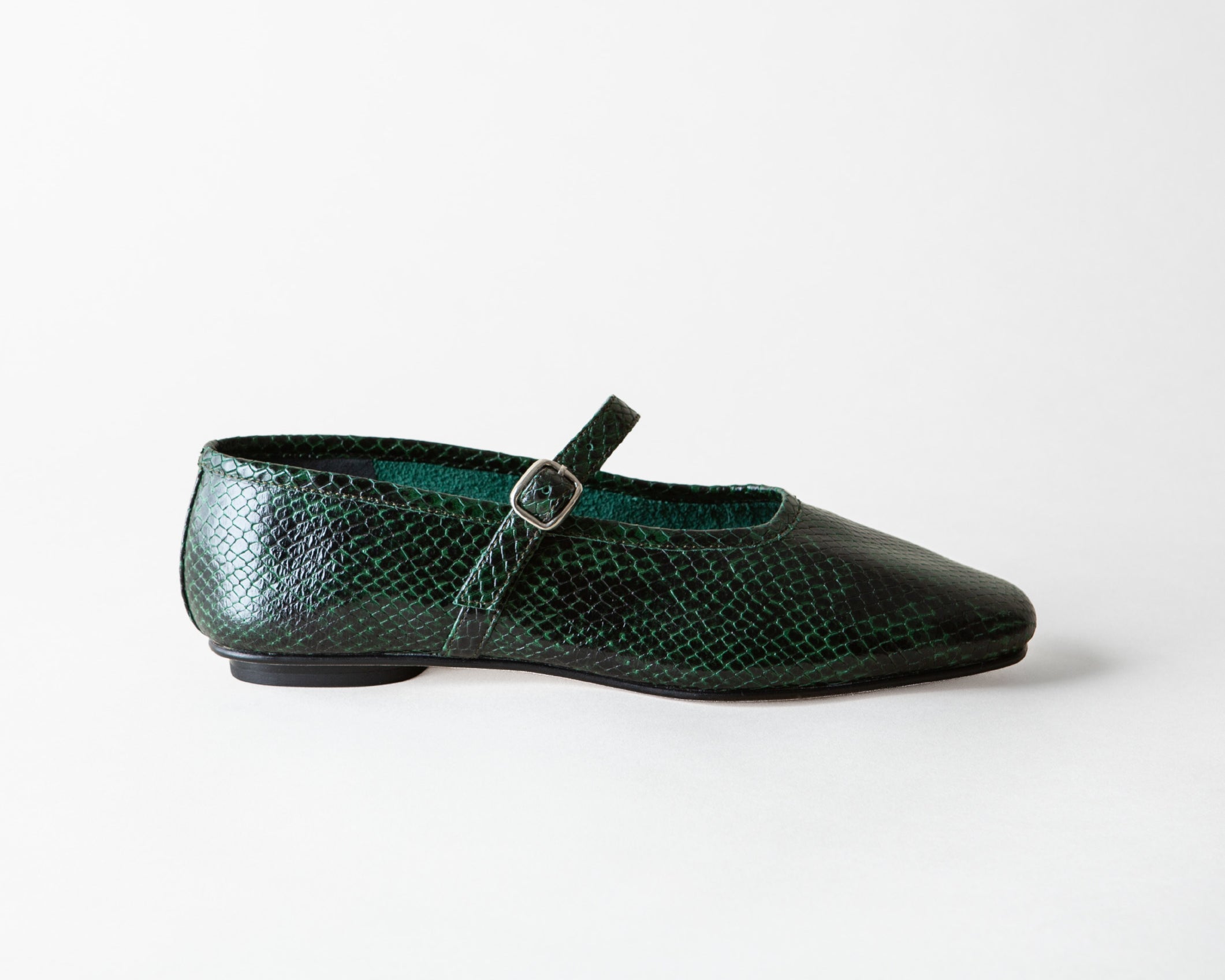 A single dark green snakeskin Mary Jane flat shoe with a pointed toe and a small silver buckle, shown in profile against a light gray background.