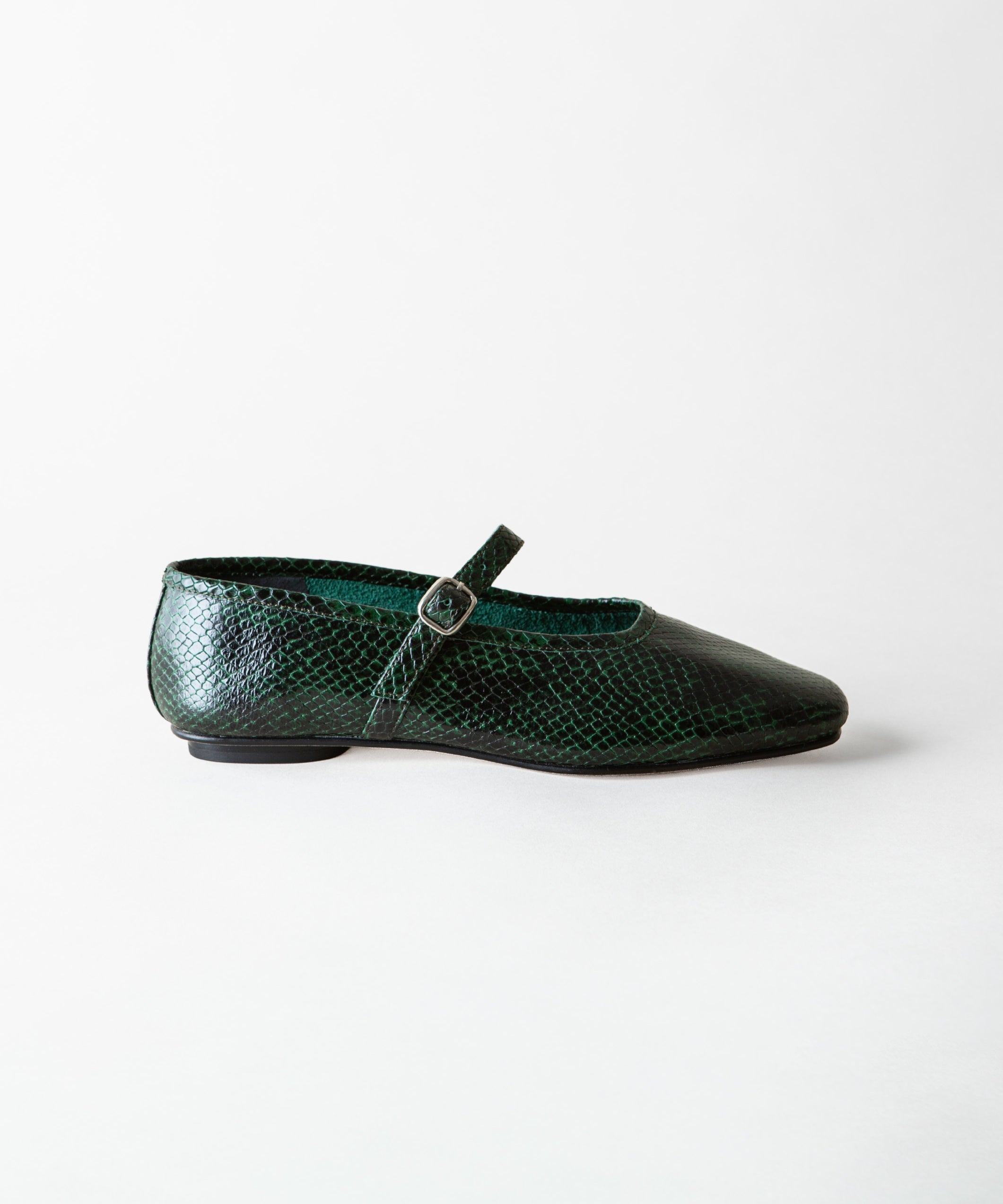 A single dark green snakeskin Mary Jane flat shoe with a pointed toe and a small silver buckle, shown in profile against a light gray background.