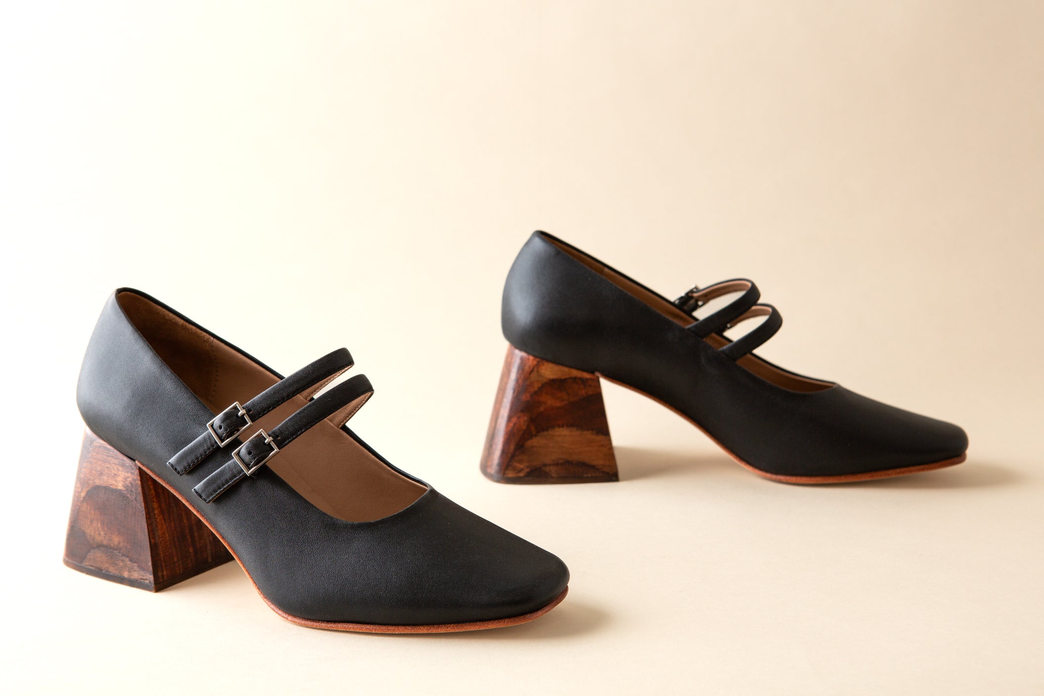 Pair of black shoes with wooden heels on a beige background