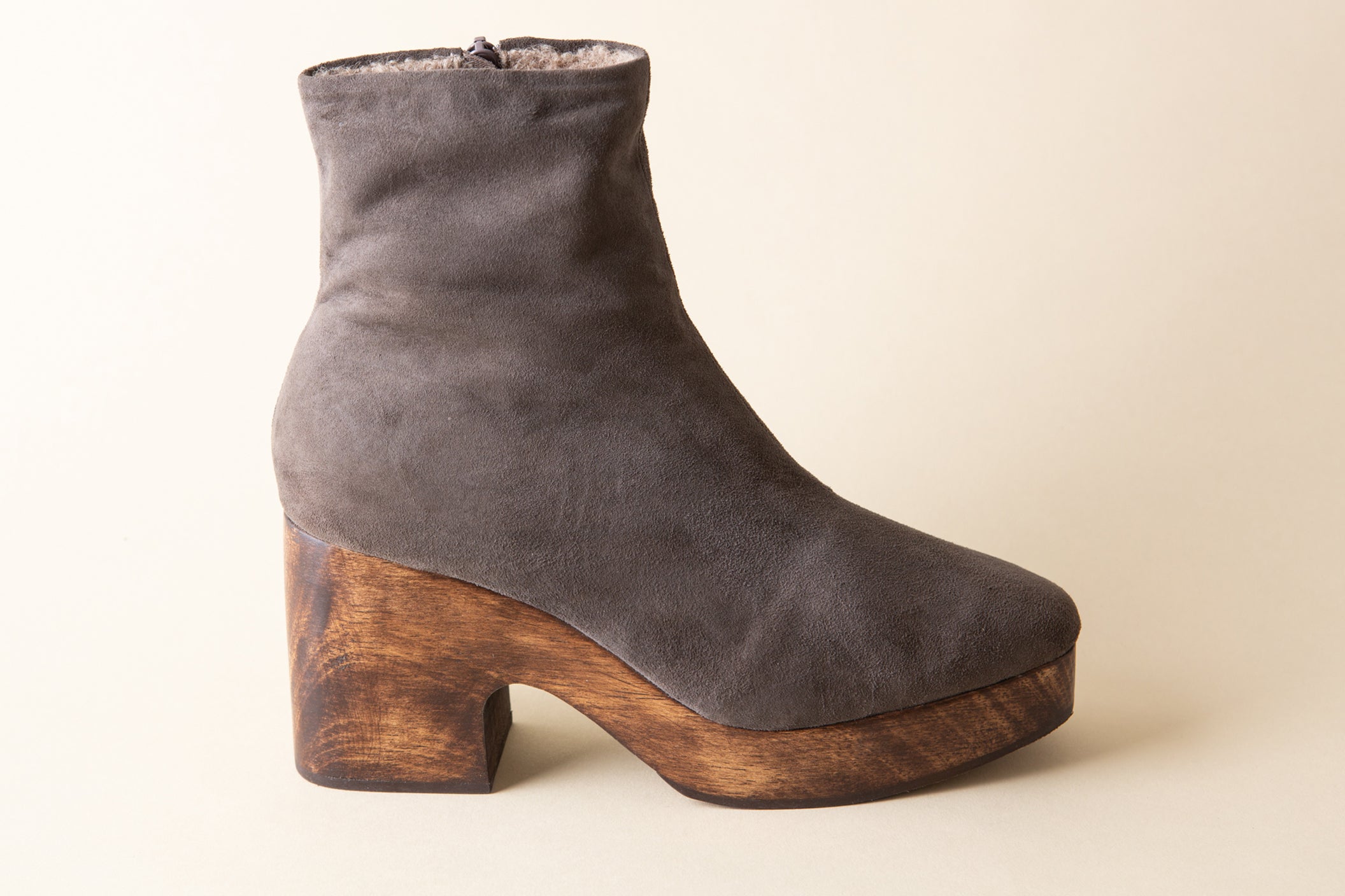 Gray suede ankle boot with wooden block heel on a beige background