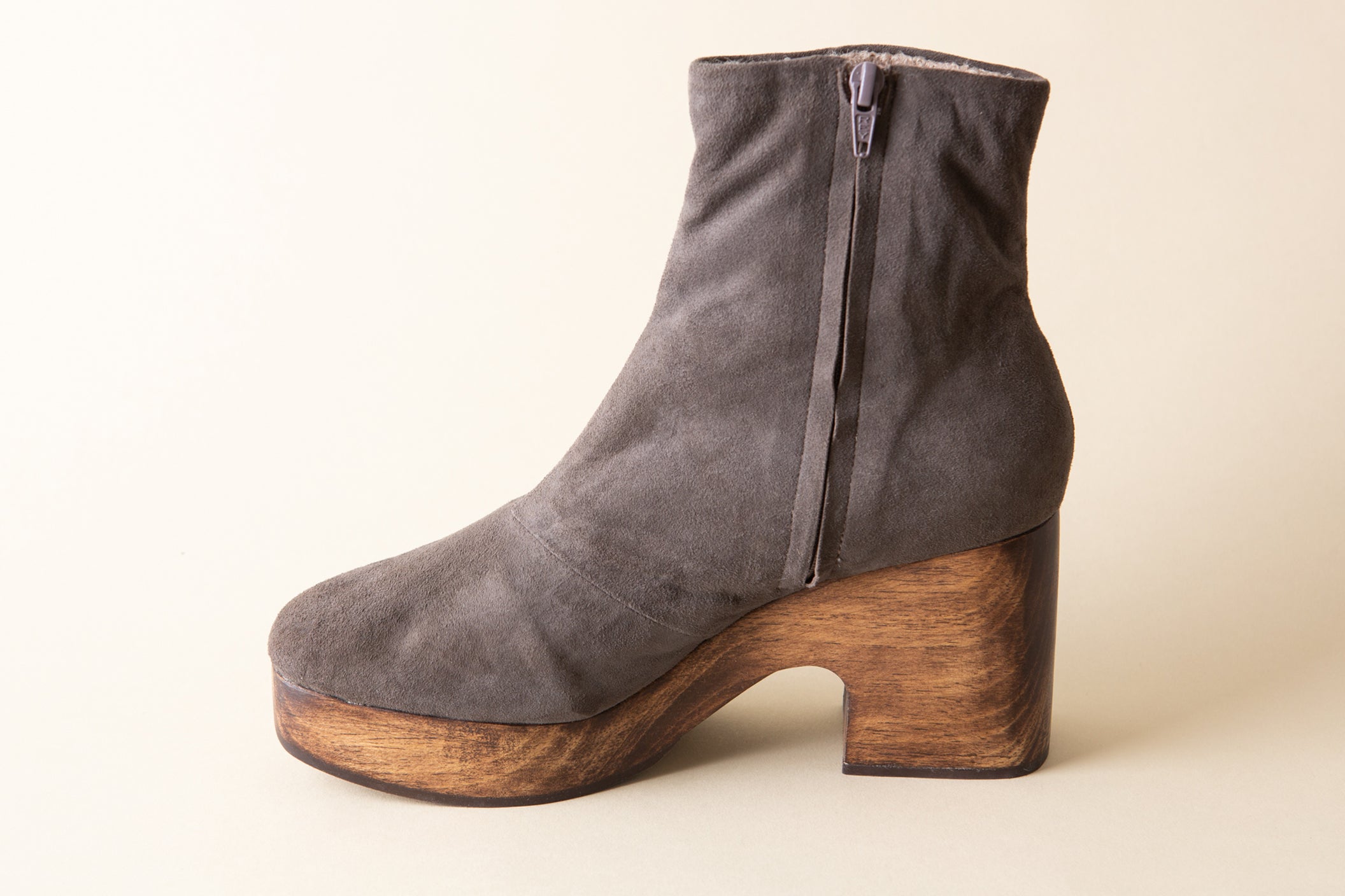 Gray suede ankle boot with wooden heel on a beige background