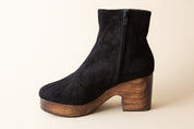 Black suede ankle boot with wooden platform sole on a beige background