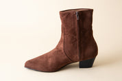 Brown suede ankle boot on a beige background