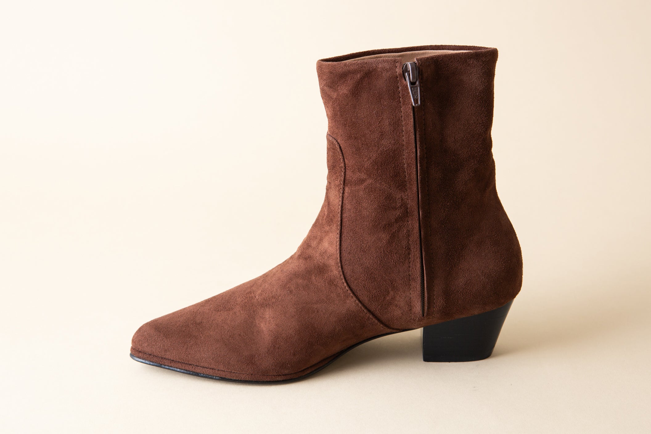 Brown suede ankle boot on a beige background